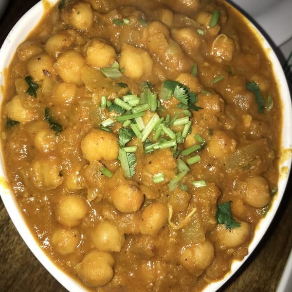 Close-up of Daawath Indian Cuisine's chana masala, a chickpea curry garnished with fresh cilantro.