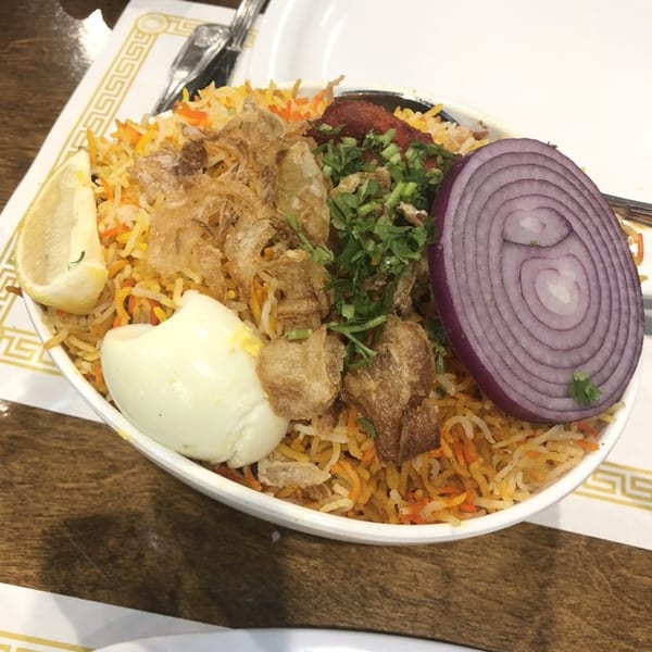 Daawath Indian Cuisine's chicken biryani with fried onions, cilantro, a hard-boiled egg, and red onion.